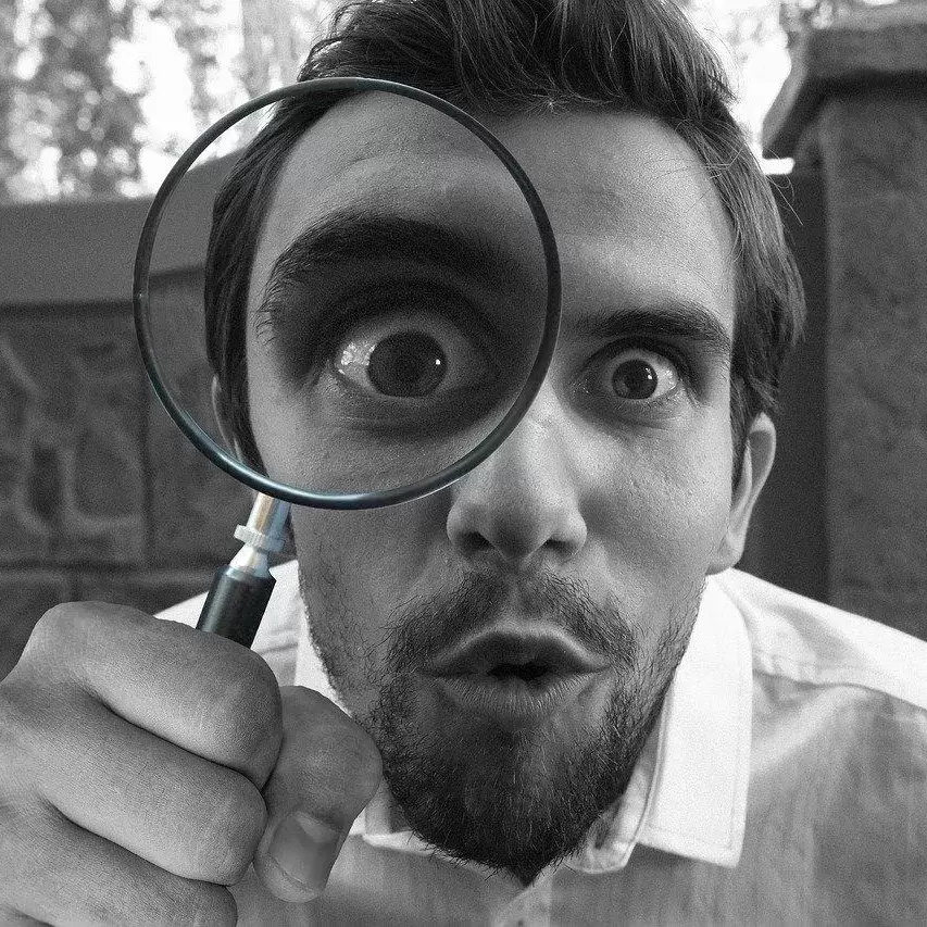 A curious man looking through a magnifying glass